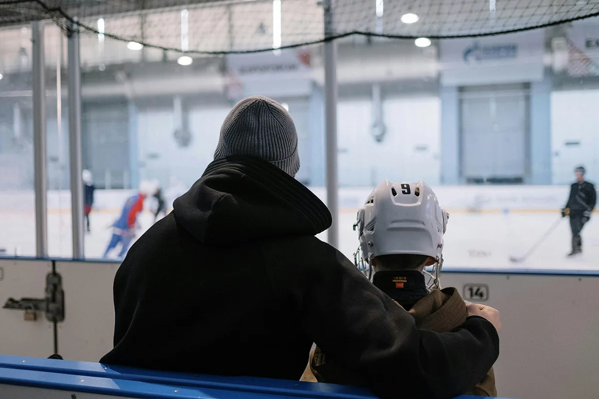 A father and son take a break at hockey practice, illustrating a section on how Maverick Wealth Management knows financial management for professional athletes, especially hockey players
