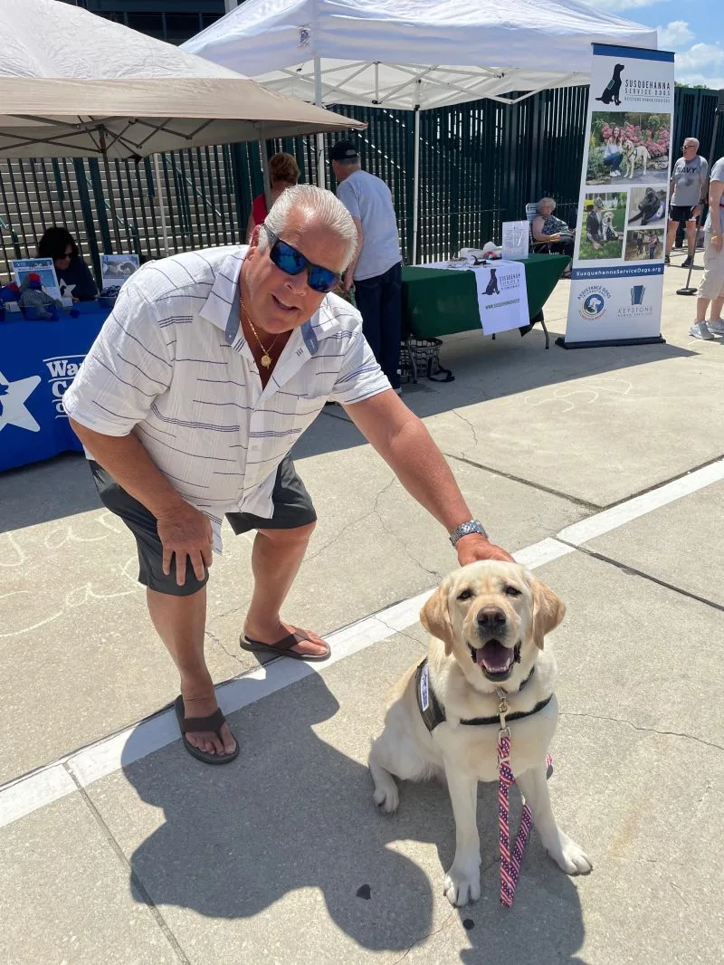 John Gallagher of Maverick Partners poses with a dog from Animal Outreach, one of the groups the Wealth Advisors support